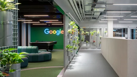 Przestrzeń biurowa z logo Google, kanapami i roślinami.