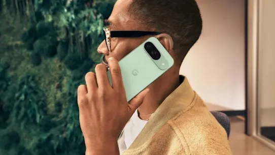 Yelek giyen gözlüklü bir kişi, mint yeşili Pixel telefonu kulağına doğru tutuyor.