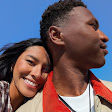 A person rests their head on another person's shoulder. Pixel 10's ultrawide camera captures the large stretch of blue sky behind them.